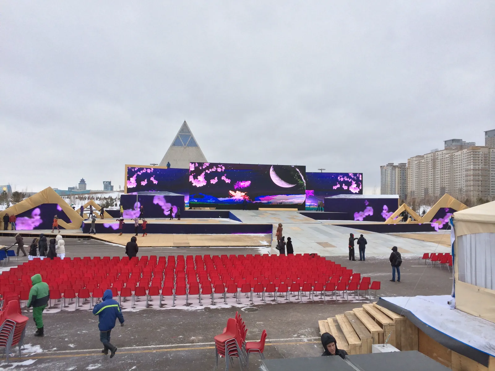 Уличная городская сцена с широкой LED-стеной зимой, новостройки на фоне